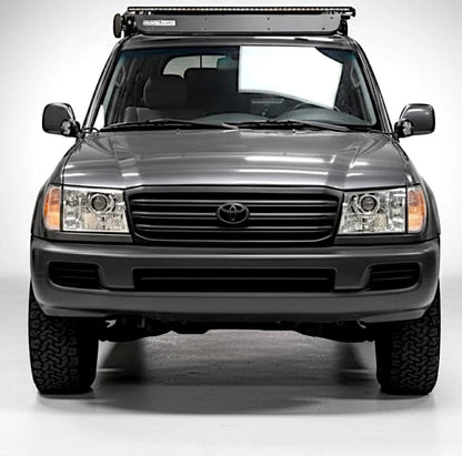 Ninja Cruiser LED projector headlights with glass lenses installed on a grey Toyota Land Cruiser 100 Series on studio background