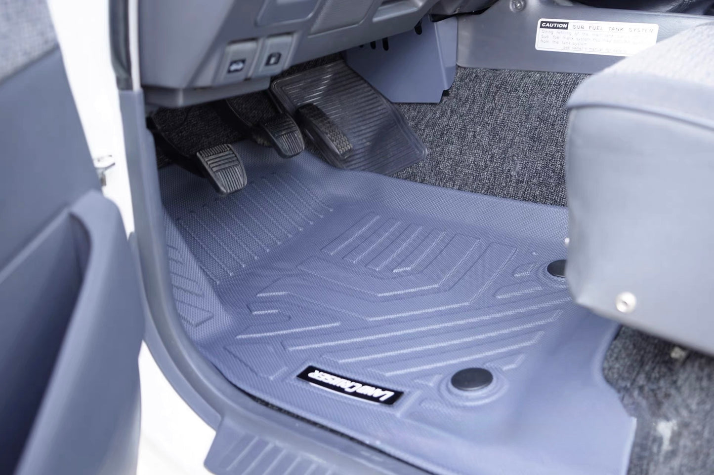 Car trunk with a set of gray floor mats featuring a brand logo Land Cruiser