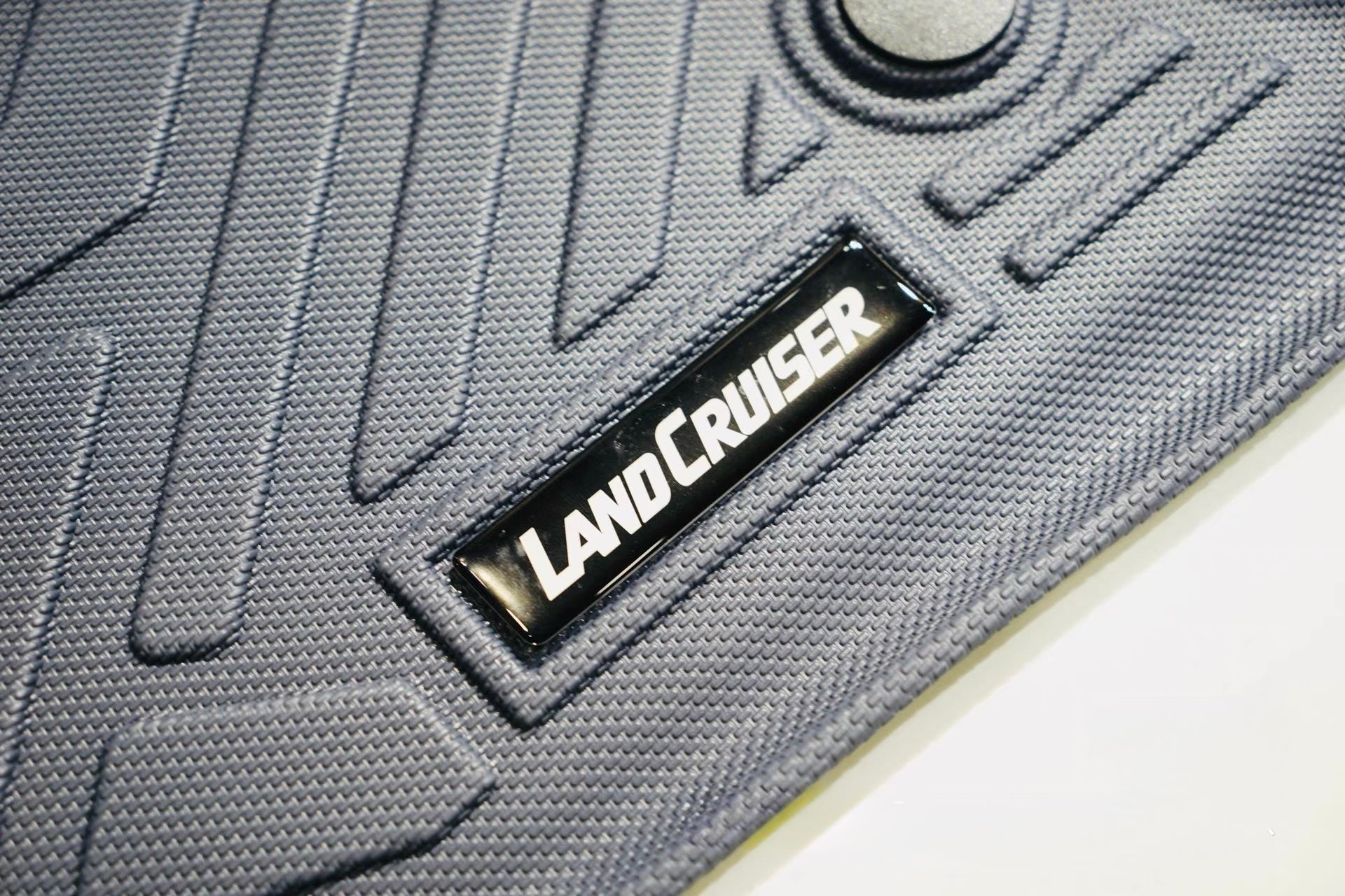 Gray car rubber mat with 'LandCruiser' logo on a white background
