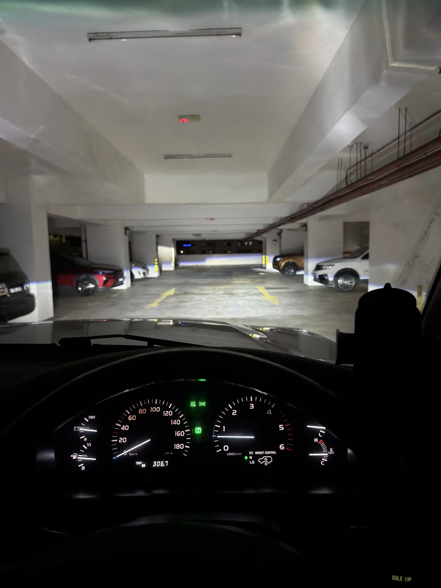 Car dashboard view at night on a dark on parking lot with powerful led headlight wide beam on the car park