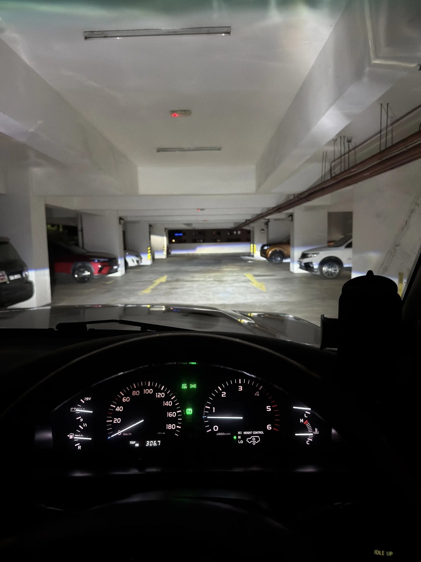 Car dashboard view at night on a dark on parking lot with powerful led headlight wide beam on the car park