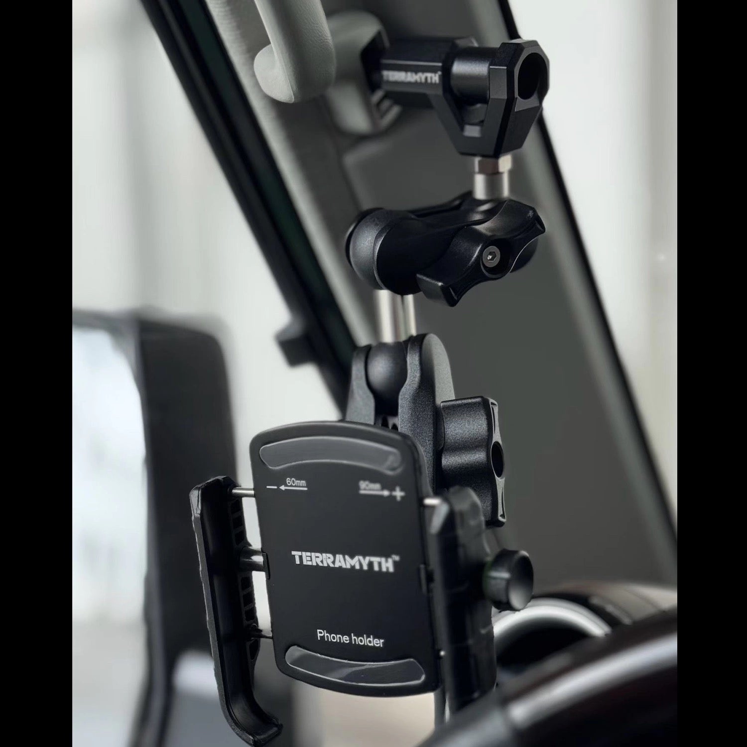 Phone holder with Terramyth branding attached to a Land Cruiser 70 series A-pillar grab handle