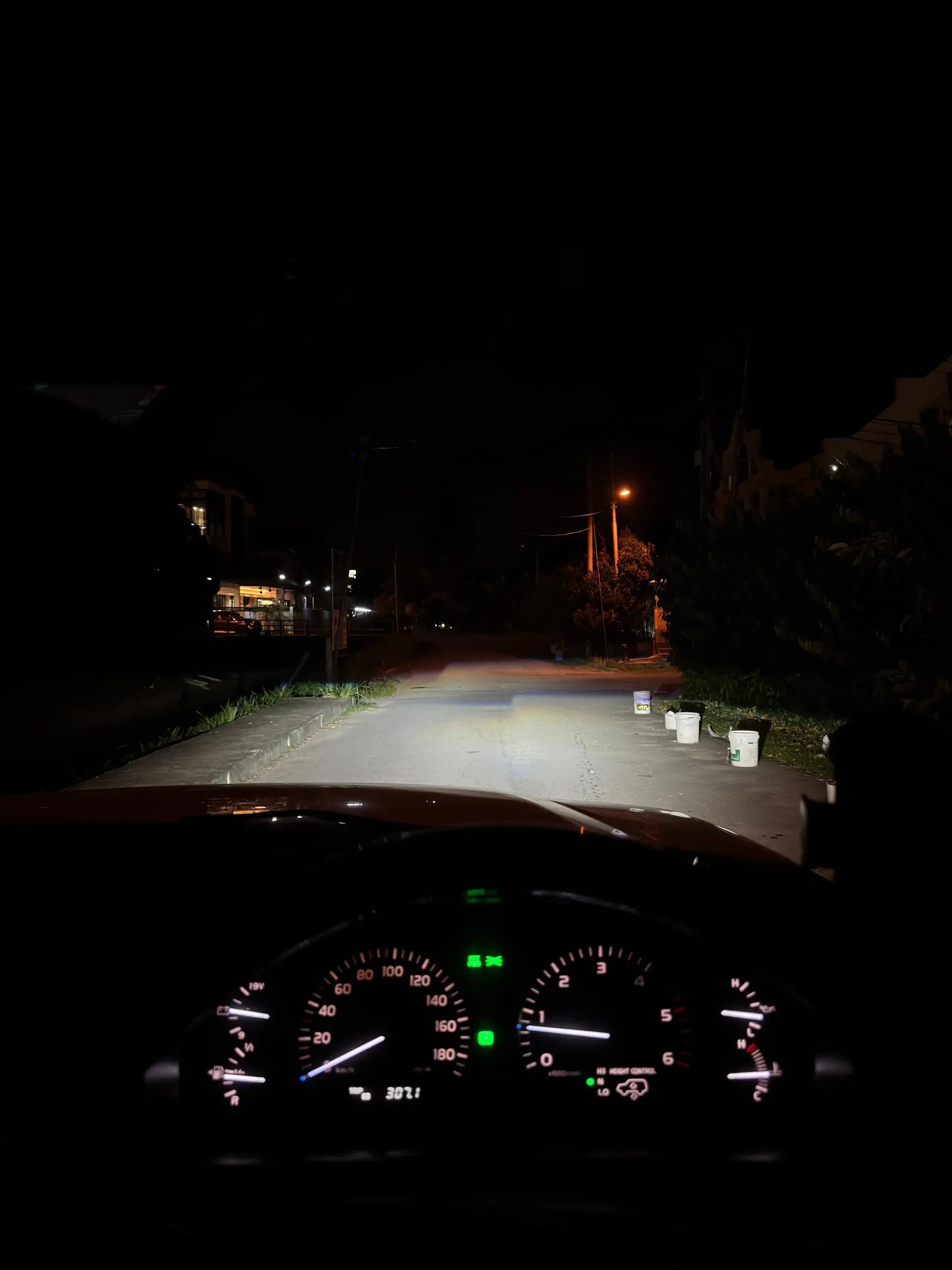 Car dashboard view at night on a dark street with powerful led headlight wide beam on the road