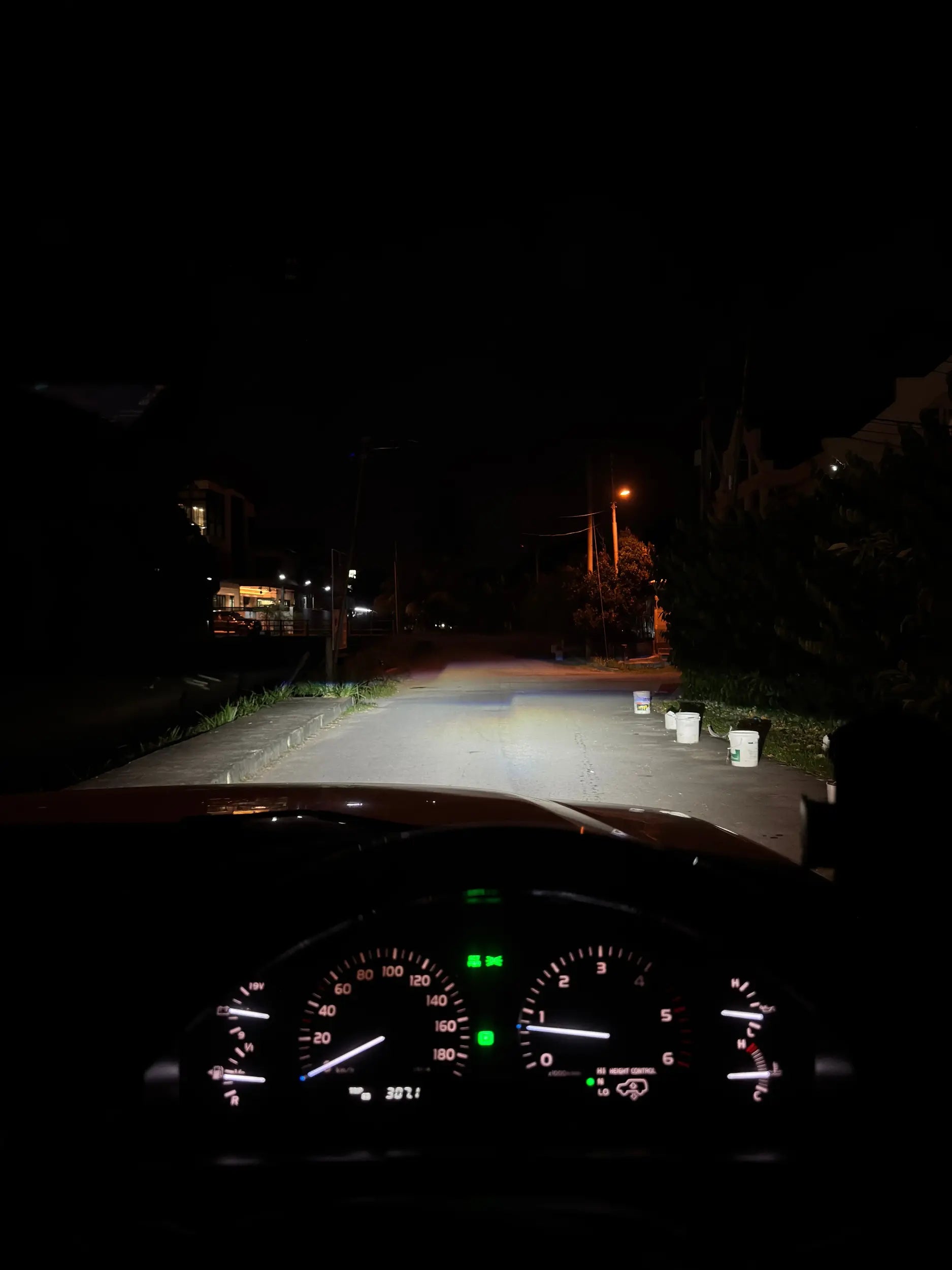 Car dashboard view at night on a dark street with powerful led headlight wide beam on the road