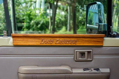 LC70 Series Wooden Door Armrest Topper - Close-up of the smooth, premium wood finish installed above the interior door panel, showing the detailed grain and window switches.
