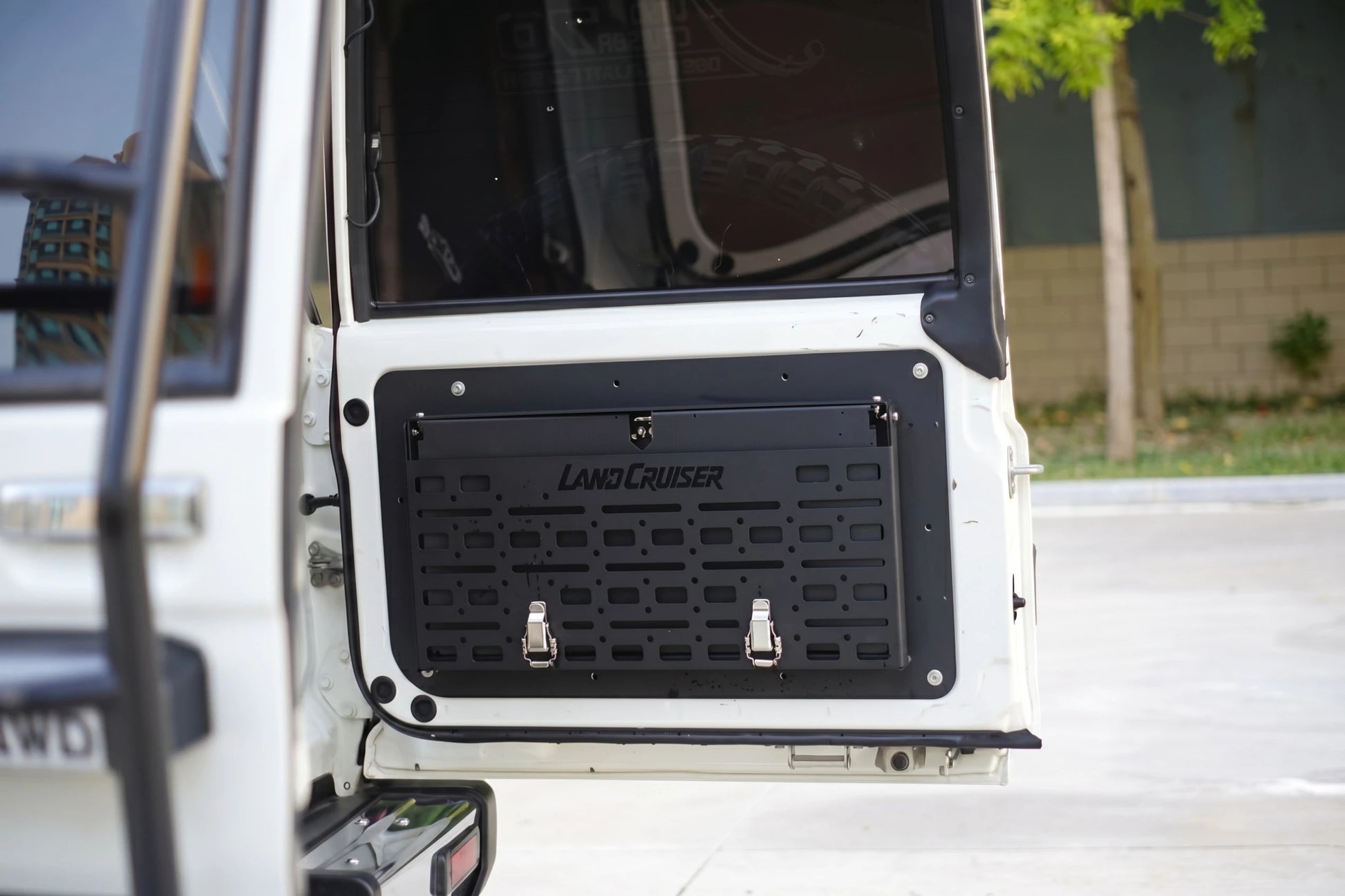 Close-up of LC76 tailgate MOLLE panel in black magnesium-aluminium alloy with latch locks