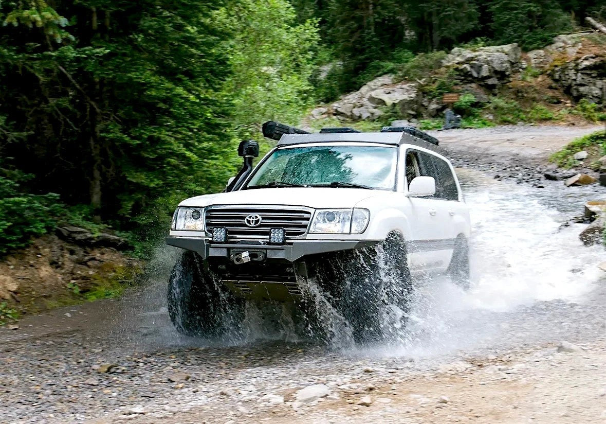 Ninja Cruiser white Toyota Land Cruiser 100 Series driving through a stream with upgraded LED projector headlights
