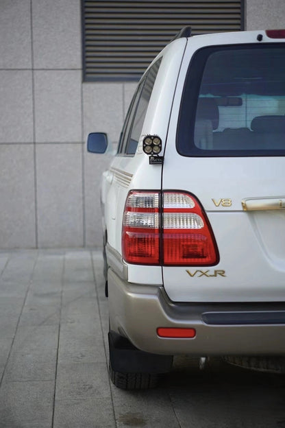 Toyota Land Cruiser 100 LC100 LX470 rear view with VXR badge showing aftermarket LED work light mounted on tailgate hinge bracket