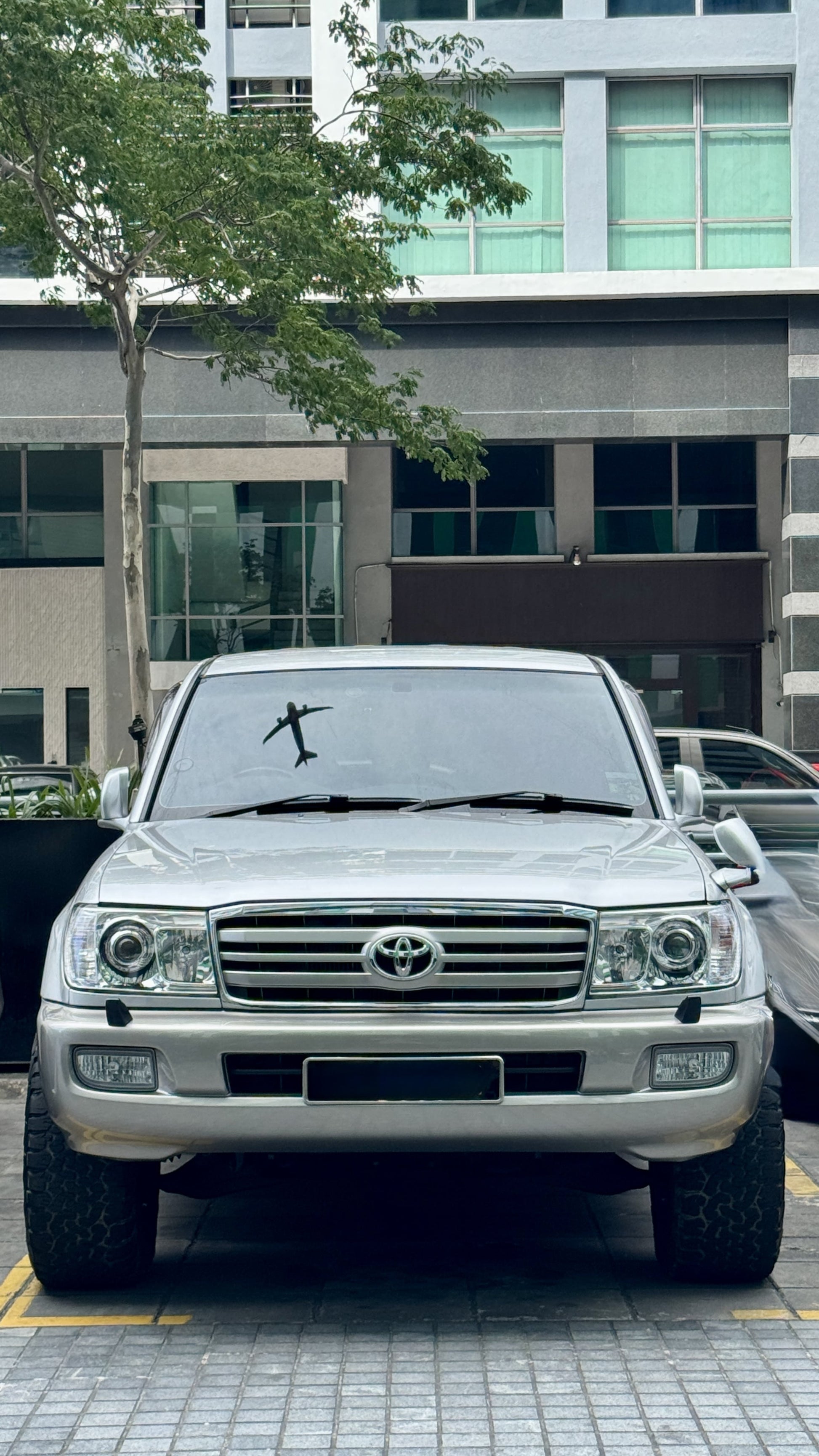 Silver Toyota Land Cruiser LC100 SUV parked on a street with a building in the background
