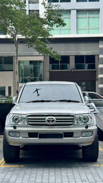 Silver Toyota Land Cruiser LC100 SUV parked on a street with a building in the background