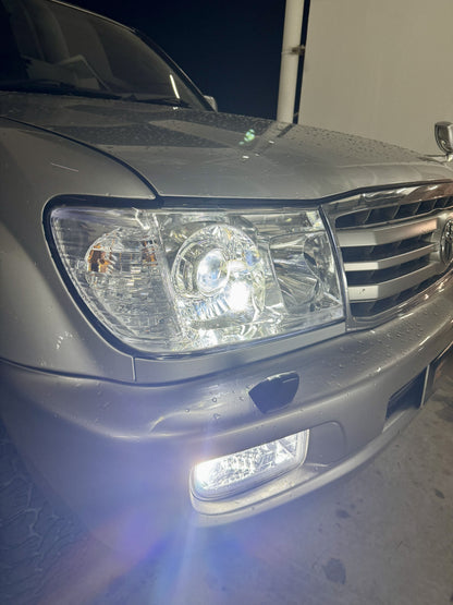 Close-up of a a LC100 front headlight and bumper fog light at night with white light