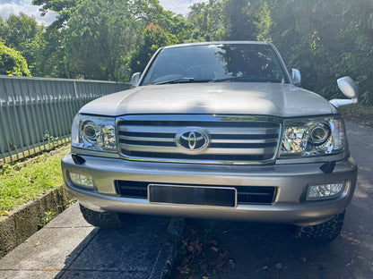 Silver Toyota SUV Land Cruiser 100 series parked on a driveway with greenery in the background